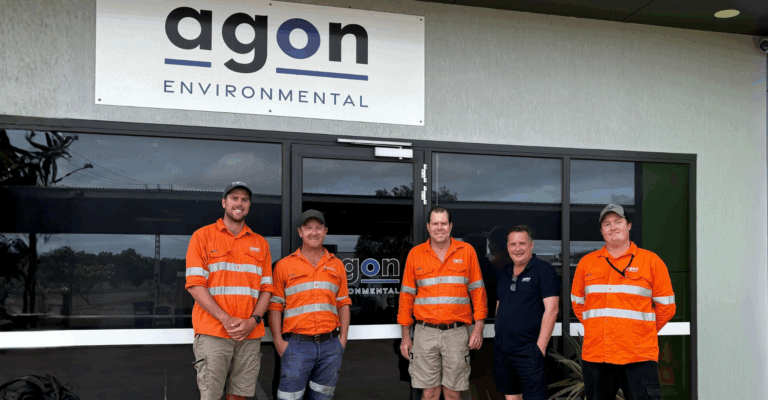 Five Agon Environmental team members standing outside the Agon Environmental office wearing high-visibility orange work uniforms.